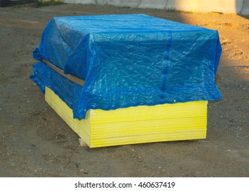 Wooden Stacked Plywood Or Gyproc Panels Covered With A Tarp On Construction Site
