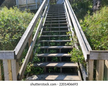 A Wooden Staircase Extending Far Up A Grass Hillside On A Sunny Day.