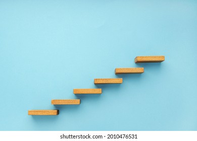 Wooden staircase on blue background. Growth, increasing business, success process concept. Copy space