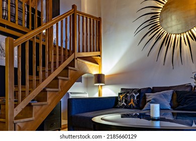 Wooden Staircase To Second Floor In Tiny Living Room, Wall Decor In The Form Of Sun, Low Angle View