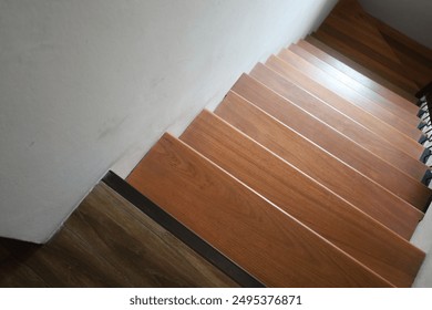 A wooden staircase with a white wall in the background. The stairs are made of wood and are brown in color. - Powered by Shutterstock