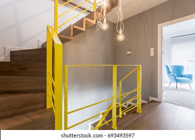 Wooden staircase with yellow railing in modern stylish entrance hallway with vintage bulb pendant light and white wall - Powered by Shutterstock