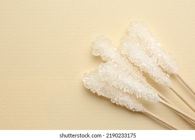 Wooden Sticks With Sugar Crystals And Space For Text On Beige Background, Flat Lay. Tasty Rock Candies