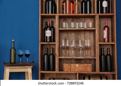 Wooden storage stand with wine bottles and glasses indoors - Shutterstock ID 738893248