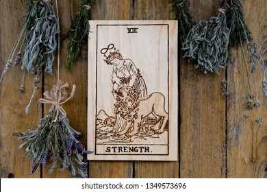 Wooden Strength Card From Tarot Major Arcana With Dried Herbs On Rustic Background - Hand Burnt In Wood By Photographer