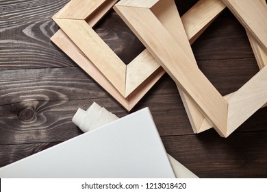 Wooden stretchers and a white blank artistic canvas lying on a dark wooden table. Wood products: Subframes. Top view - Shutterstock ID 1213018420