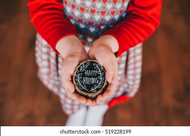 wooden stump in children's hands with the words, happy holidays