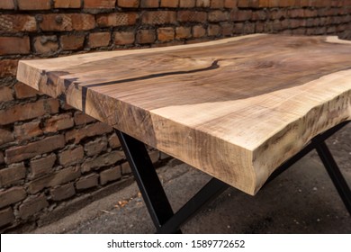 Wooden stylish table made of solid walnut with epoxy resin on the background of a brick wall