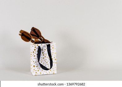 Wooden sunglasses of different design in shopping bag on grey background. Copy space for text. Sunglasses sale concept