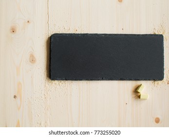 wooden surface and a flat rectangular stone from slate on it with yellow crayons for inscription, a place for advertising. construction work concept