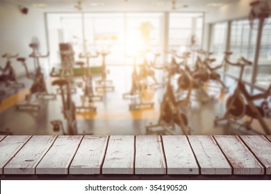 Wooden Table Against Large Empty Fitness Studio With Spin Bikes