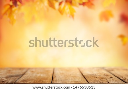  Wooden table and blurred Autumn background. Autumn concept with red-yellow leaves background.