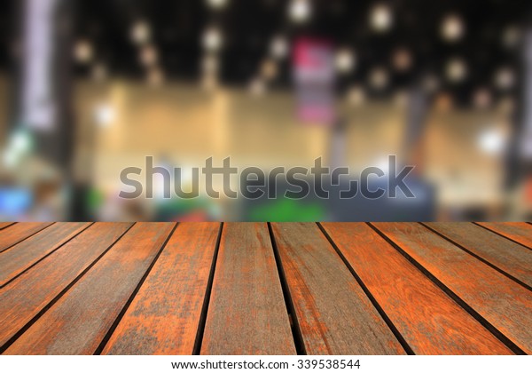 Wooden table and blurred image of motor\
show,show room,motor expo for\
background