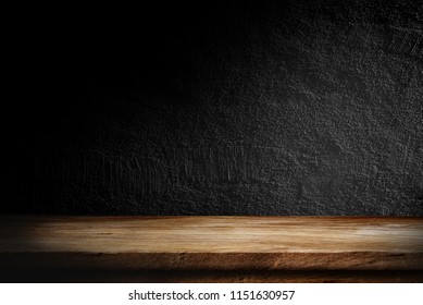 Wooden table in dark room background concept for advertising.