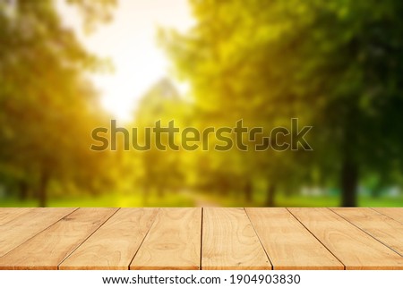 Wooden table is empty and trees and blurred in background agriculture farm - can be used to display or montage your products.