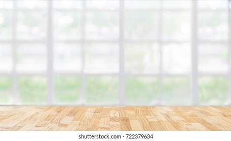 wooden table in front of abstract Blur white green background from office window