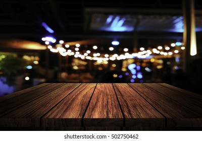 Wooden Table In Front Of Abstract Blurred Background Of Resturant Lights 