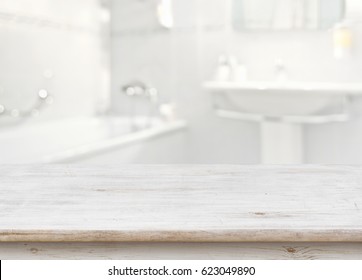 Wooden Table In Front Of Blurred Bathroom Interior As Background.