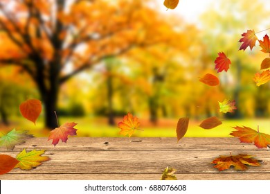 wooden table in front of a colorful autumn landscape, beautiful autumn background concept with fall leaves and advertising space - Shutterstock ID 688076608
