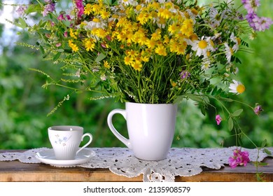 Wooden Table In The Garden, Tea, Coffee In A Mug, Bouquet Of Wildflowers, Concept Of An Outdoor Tea Party, Good Weather, A Cozy Summer Mood