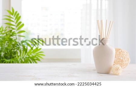 Wooden table and incense sticks vase on blurred window background