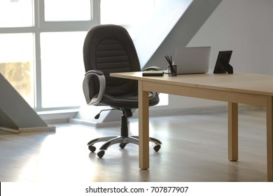 Wooden Table With Laptop And Chair In Office