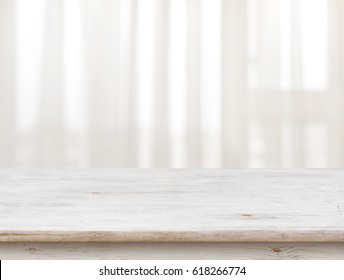 Wooden table on defocuced window with transparent curtain background.