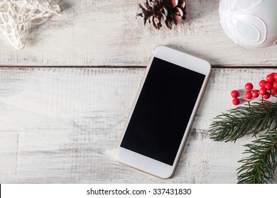 The Wooden Table With A Phone And  Christmas Decorations. Christmas Mockup Concept