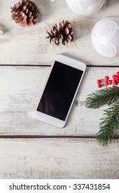 The Wooden Table With A Phone And  Christmas Decorations. Christmas Mockup Concept