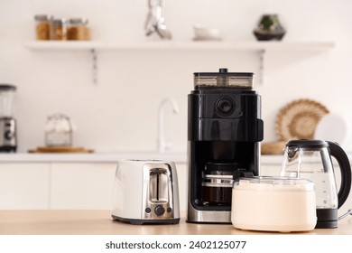 Wooden table with set of modern appliances in light kitchen - Powered by Shutterstock