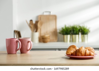Wooden table in a sunny kitchen in the morning light during breakfast - Shutterstock ID 1697985289