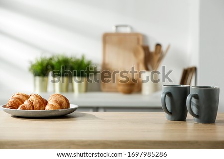 Wooden table in a sunny kitchen in the morning light during breakfast