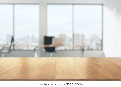 Wooden table in sunny office with big windows