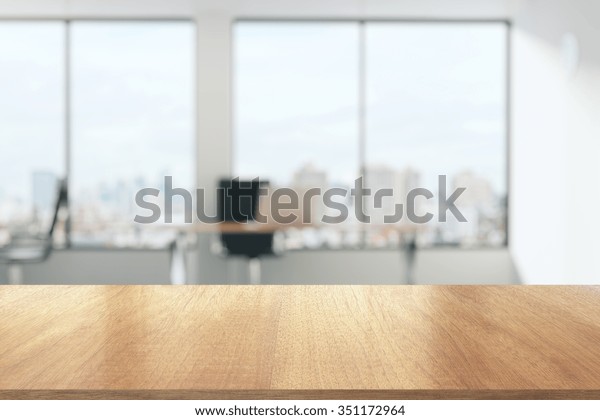 Wooden table in\
sunny office with big\
windows