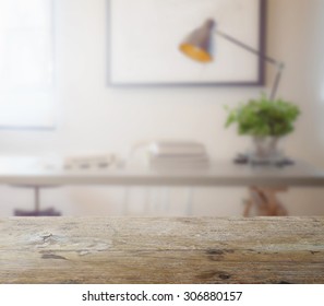 wooden table top with blur of modern working table with book and lamp as background