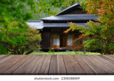 Wooden table top with blurred garden and japan house.	      