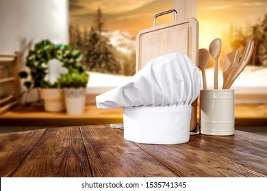 Wooden Table Top With A Blurred Kitchen Background And Snowy Winter View Outside The Window. Empty Space For Decoration And Advertising Products.