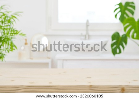 Wooden table top and defocused bathroom sink counter as background