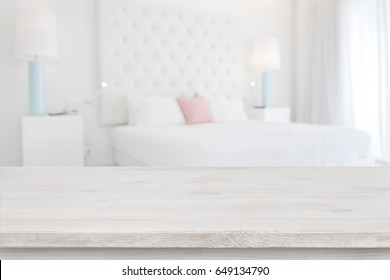 Wooden table top in front of blurred bedroom interior background