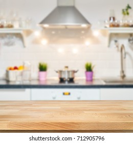 A Wooden Table Top Of The Kitchen Table On A Blurry Background Of The Kitchen Interior. Bright Interior Decoration Of Home Cooking. Bright Ready-made Picture For Your Individual Design