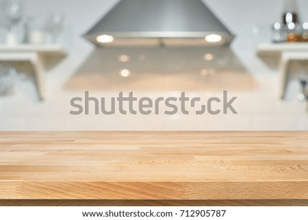 A wooden table top of the kitchen table on a blurry background of the kitchen interior. Bright interior decoration of home cooking. Bright ready-made picture for your individual design