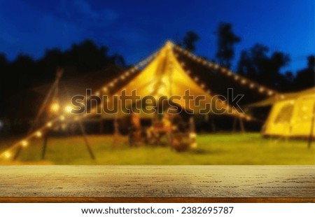 Wooden table top on blur tent camping travel tent at night.Drink and party concept.For montage product display or design key visual layout.View of copy space.