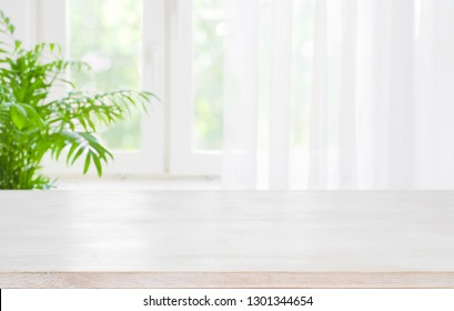 Wooden table top on blurred background of half curtained window
