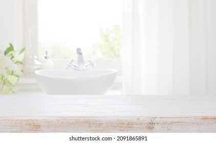 Wooden table top on blurred bathroom sink and curtained window
