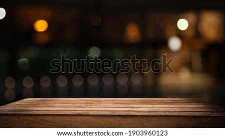 Wooden table top on blurred shop window of cafe with light bulb. Background for product display montage or key visual design.