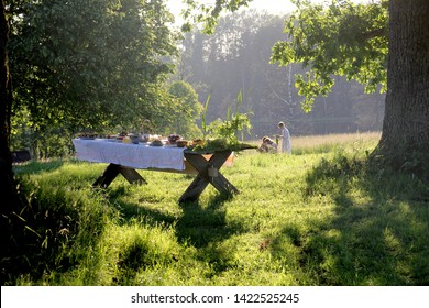 Wooden Table Under Oaks With Traditional Latvian Food. Old Latvian Culture Tradition LIGO. Midsummer Night Celebrating In Latvia. 