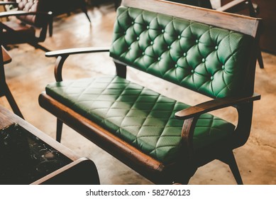 Wooden tables and luxury chairs in vintage retro style. Vintage room with wallpaper and old fashioned armchair. Luxurious brown leather texture furniture with buttons in Rustic interior design.