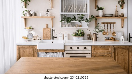 wooden tabletop with empty space on kitchen background. cozy interior with home decor, kitchenware, utensils, plates on shelf and green plants - Powered by Shutterstock