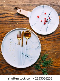 Wooden tableware, overhead flat lay shot with white marble plate and marble tray with wooden handle and cutlery set spoon, fork, knife. Gold colors. Scandinavian style - Shutterstock ID 2253036233