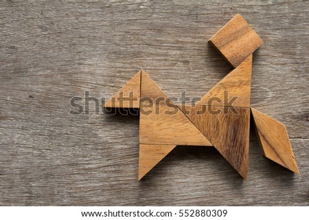Wooden tangram as man ride the horse shape on old wood background